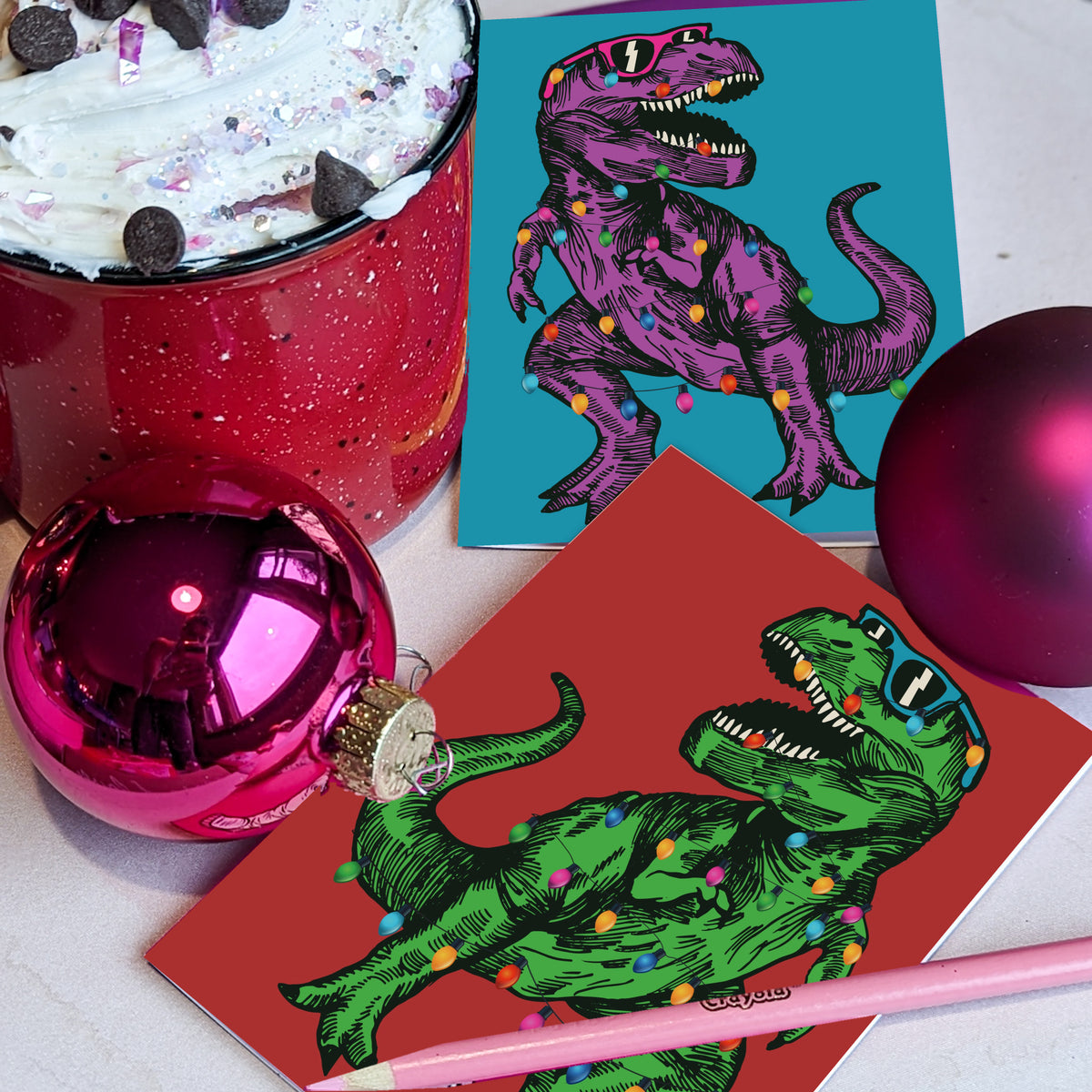 Christmas cards, two T-Rex designs with black-lens wayfarers and looped strand of red, orange, yellow, green, blue, and pink