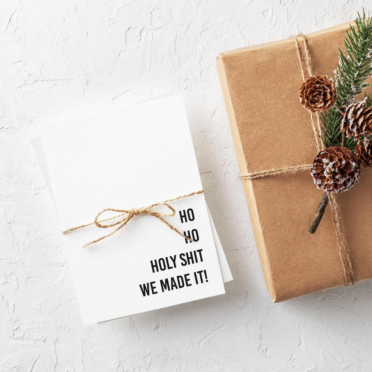 White folded Christmas cards with blunt holiday phrases in bold black sans-serif, sold as a 24-card set.
