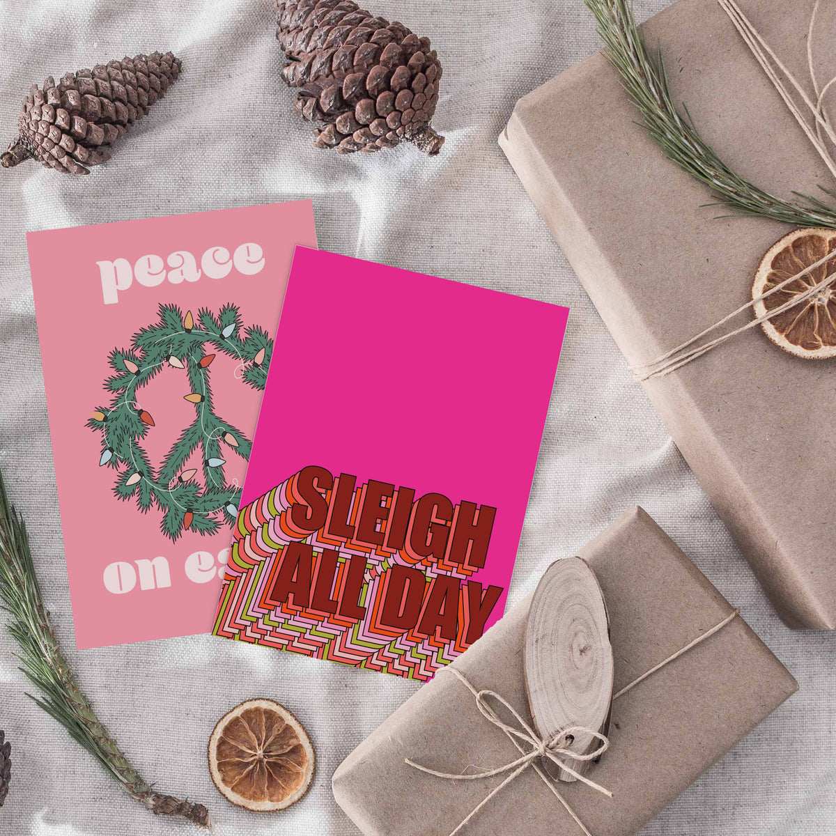 Pink Christmas card set with retro lettering styles including striped block type, cursive script, and bold sans-serif.