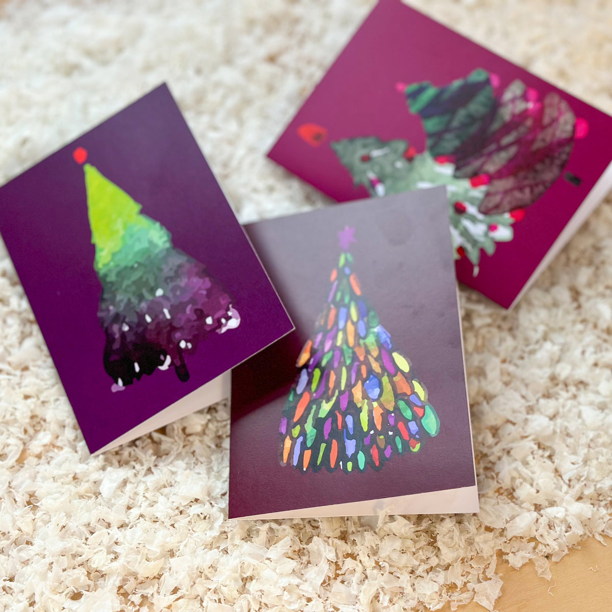 Christmas cards featuring abstract trees rendered as daubs, cross-hatching, and layered geometric shapes.