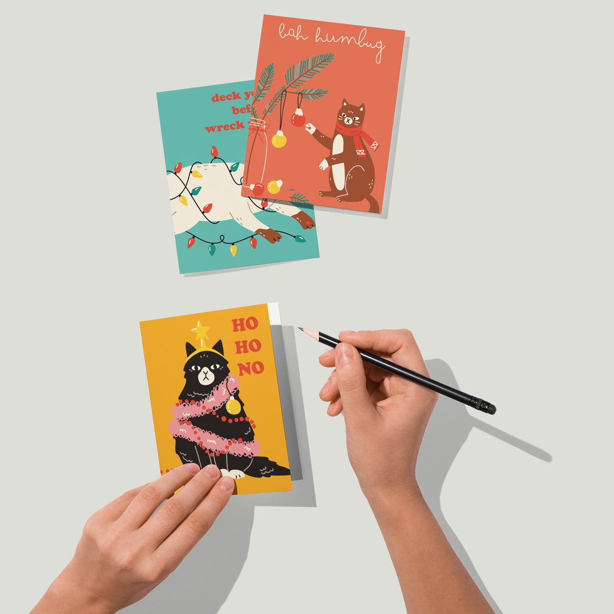 Holiday greeting cards with illustrated cats and captions such as Merry Catmas and I'm Feline Festive.