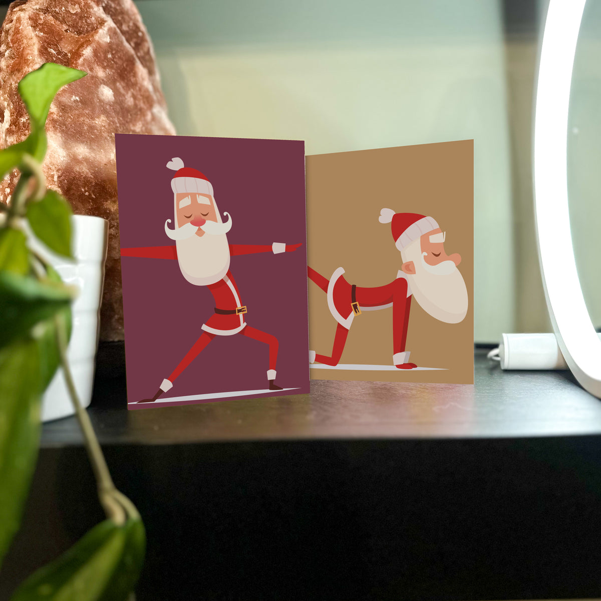 Six illustrated Santa yoga pose designs on solid colored backgrounds, packaged as a set of 24 holiday cards.