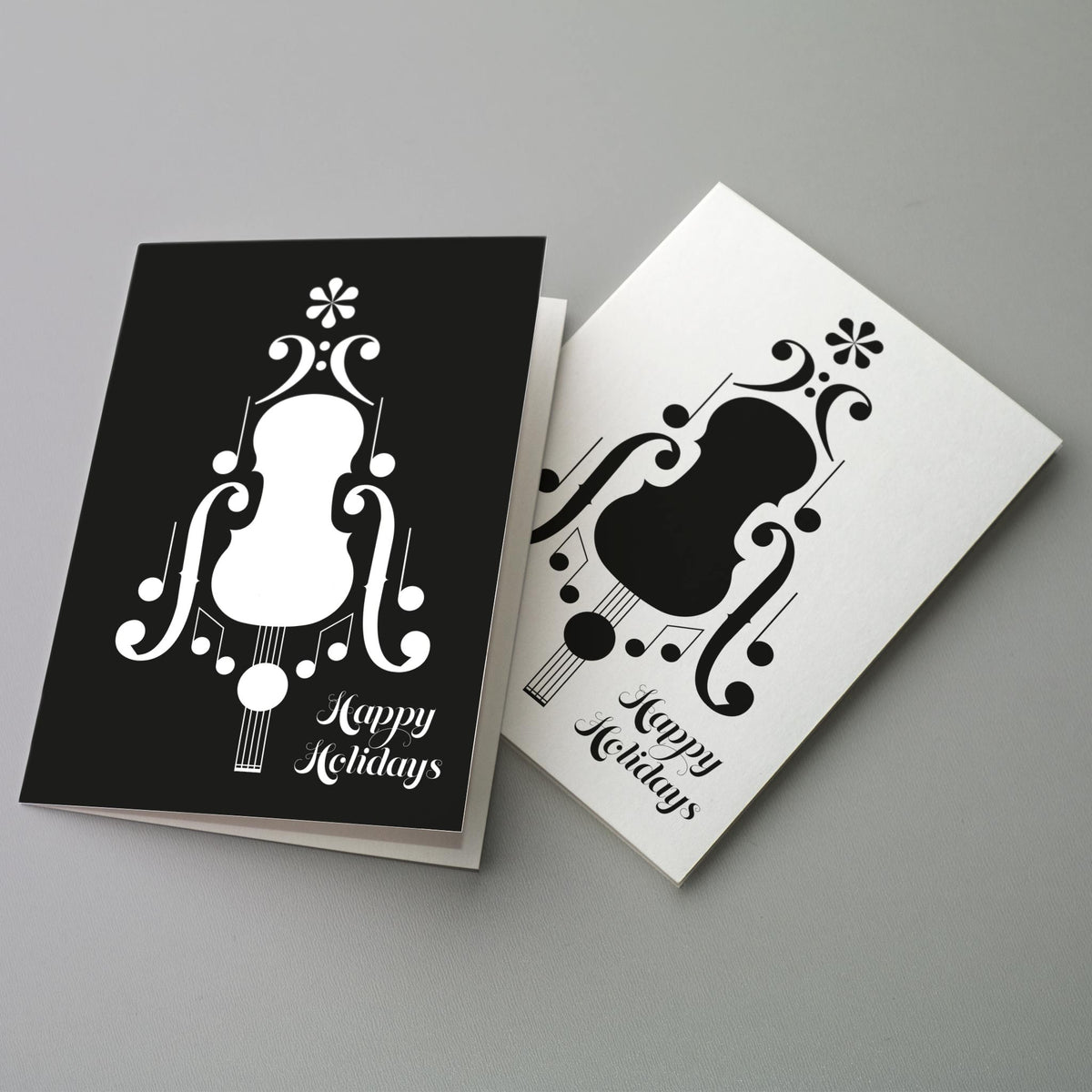 Set of 24 holiday cards in two designs: string instrument body formed from clefs, f-holes, and noteheads on black or white.