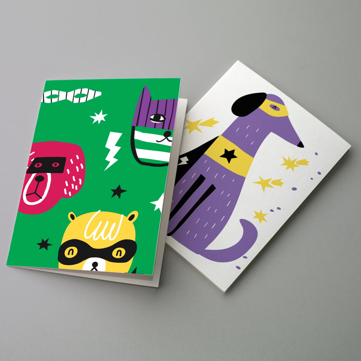 Two alternating card designs featuring cartoon animals wearing superhero costumes with stars and lightning bolts.
