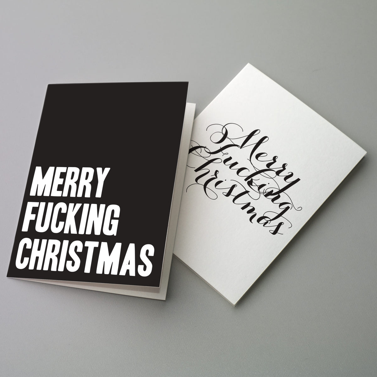 Holiday cards reading "Merry Fucking Christmas" in block caps or script on black or white cardstock, 24 count.