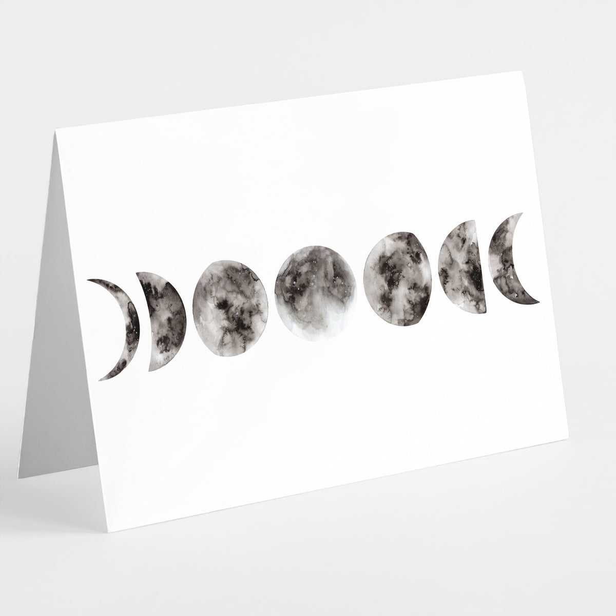 Set of 24 folded notecards printed with a watercolor-style moon phases sequence in monochrome.