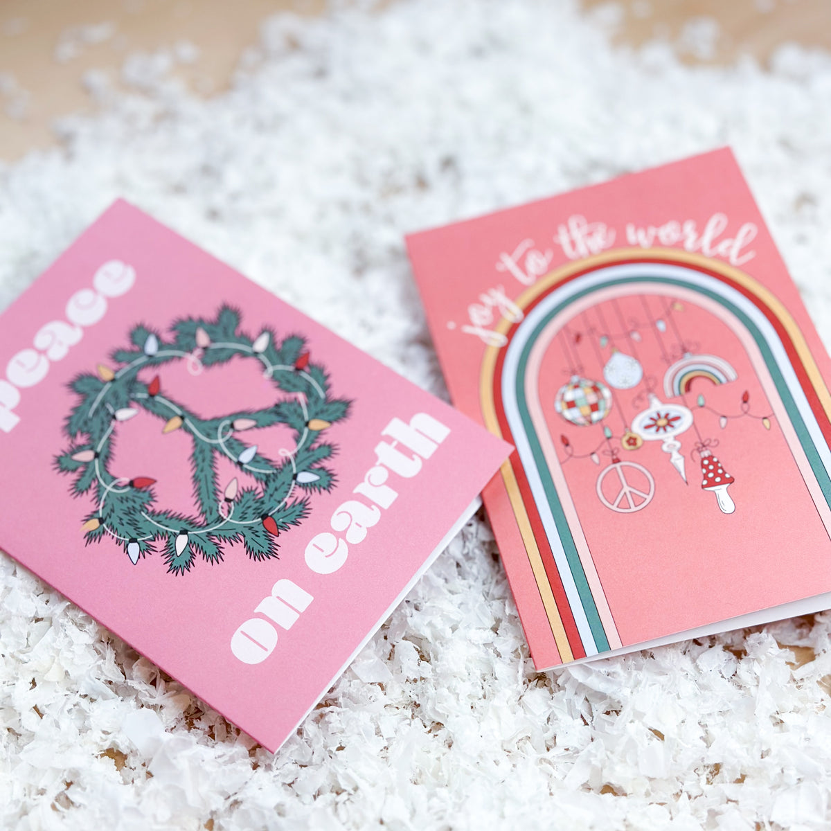 Christmas card set in pink, coral, and magenta with retro block lettering and watercolor animal illustrations.