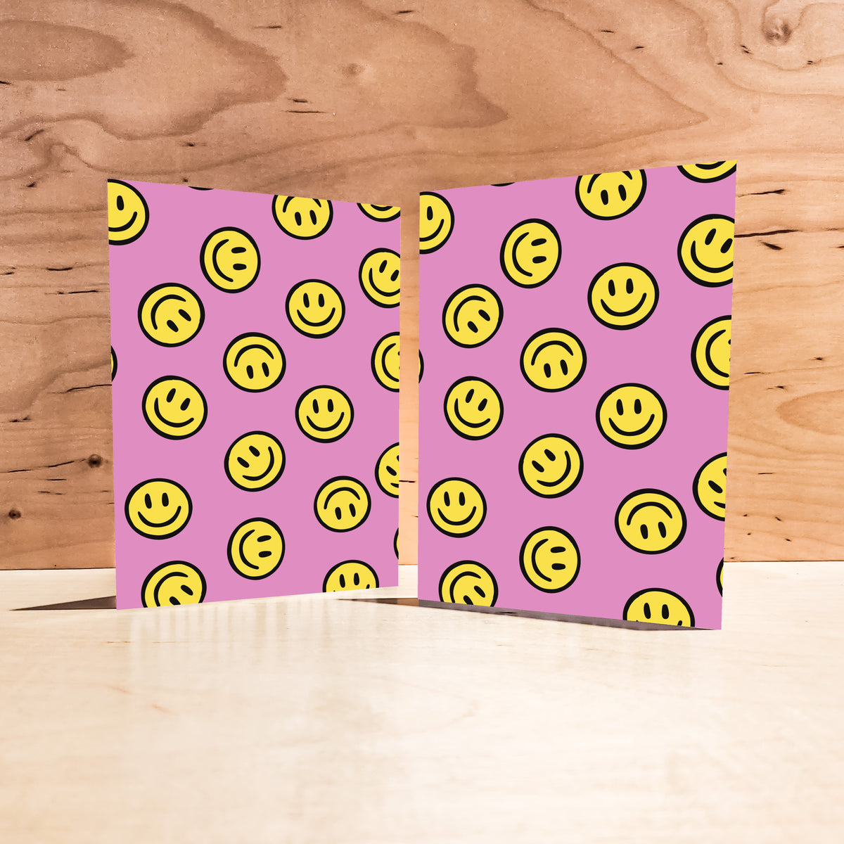Pink notecards printed with an all-over pattern of yellow smiley face graphics.