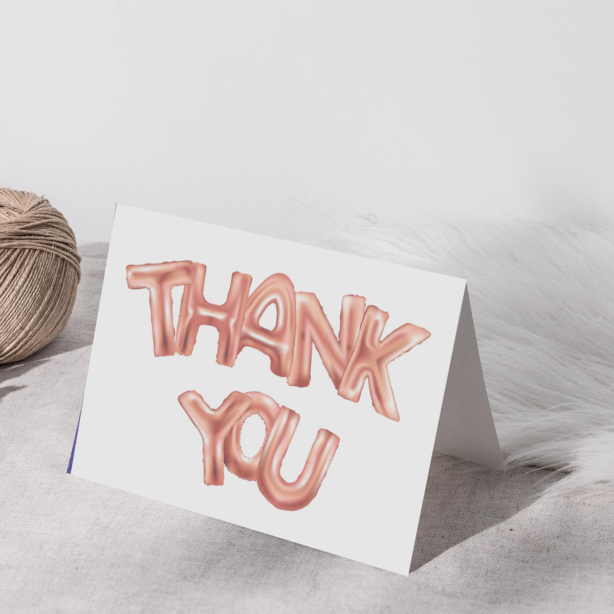 White folded cards printed with THANK YOU in large-scale rose gold balloon lettering.