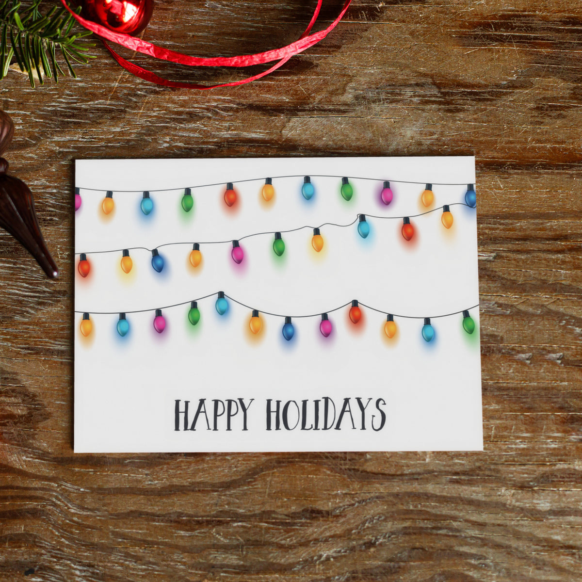 White card with three catenary strands of classic string light bulbs glowing against a white background.