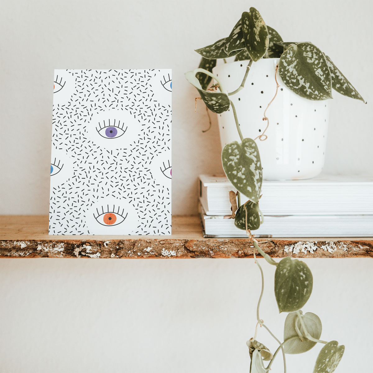 Abstract eye-print cards with black dash accents and colored irises arranged across the card front.