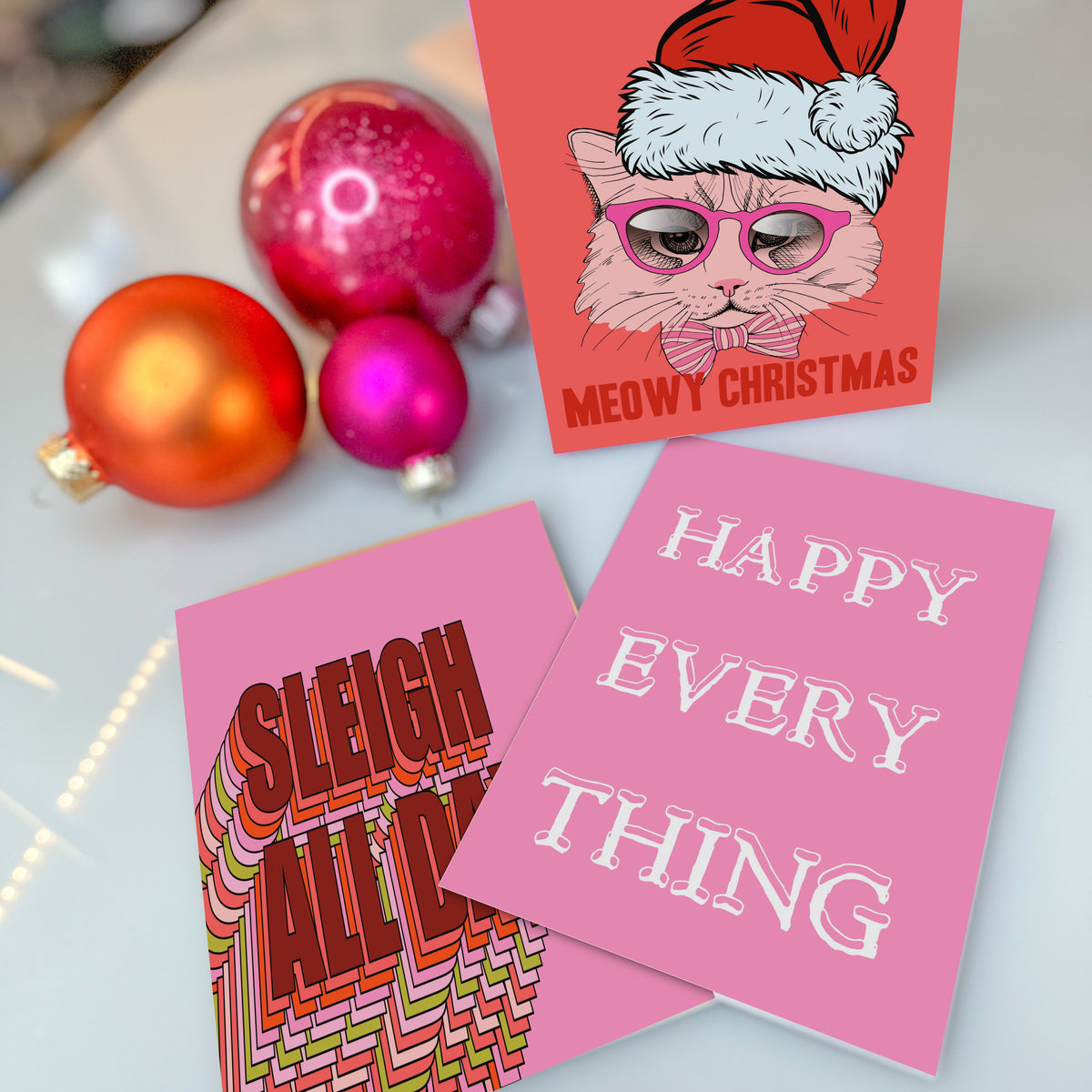 Christmas card assortment including sincere, humorous, and profanity-themed designs in a saturated pink and coral palette.