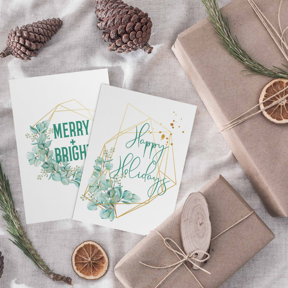 Folded holiday note cards with botanical motifs, leaf wreaths, and eucalyptus branches in green and teal tones.