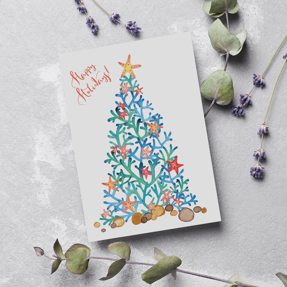 Holiday cards featuring a Christmas tree silhouette made of coral branches, topped with a yellow-centered starfish.