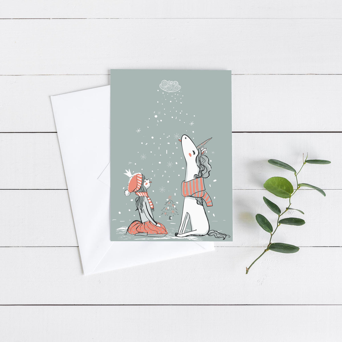 Line-drawn girl in red skirt and striped hat facing a scarved unicorn, small tree between them, gray card background.