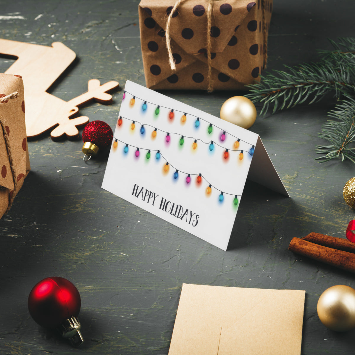 Card set, one design, landscape orientation, string lights in mixed colors above bold brushy holiday text.