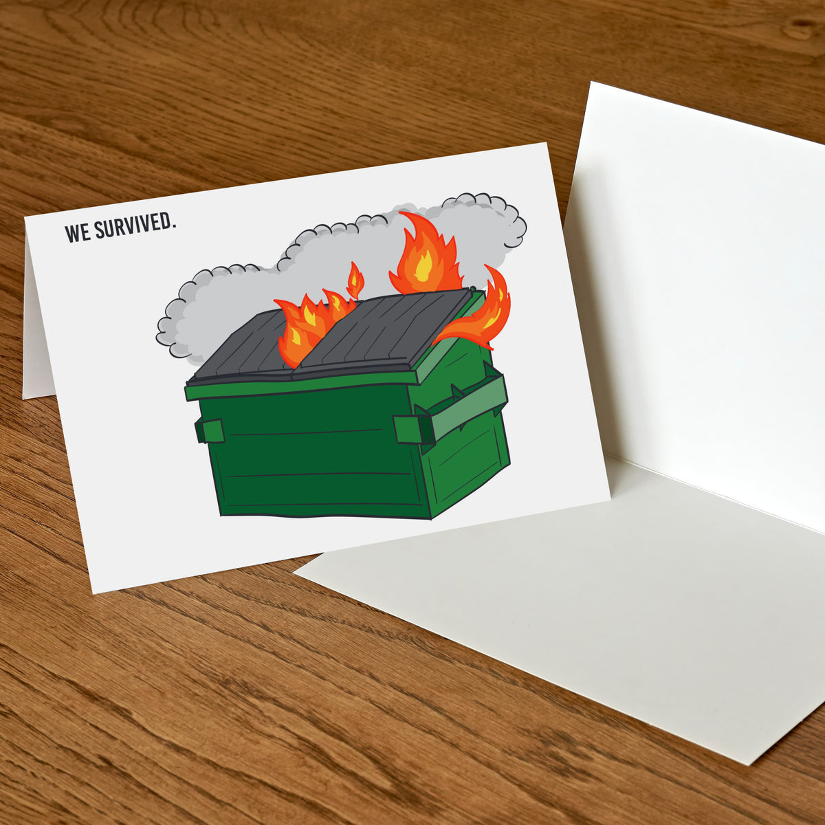 White card showing a flat illustrated green dumpster with a charcoal lid, flames, and gray smoke, with WE SURVIVED. in black.