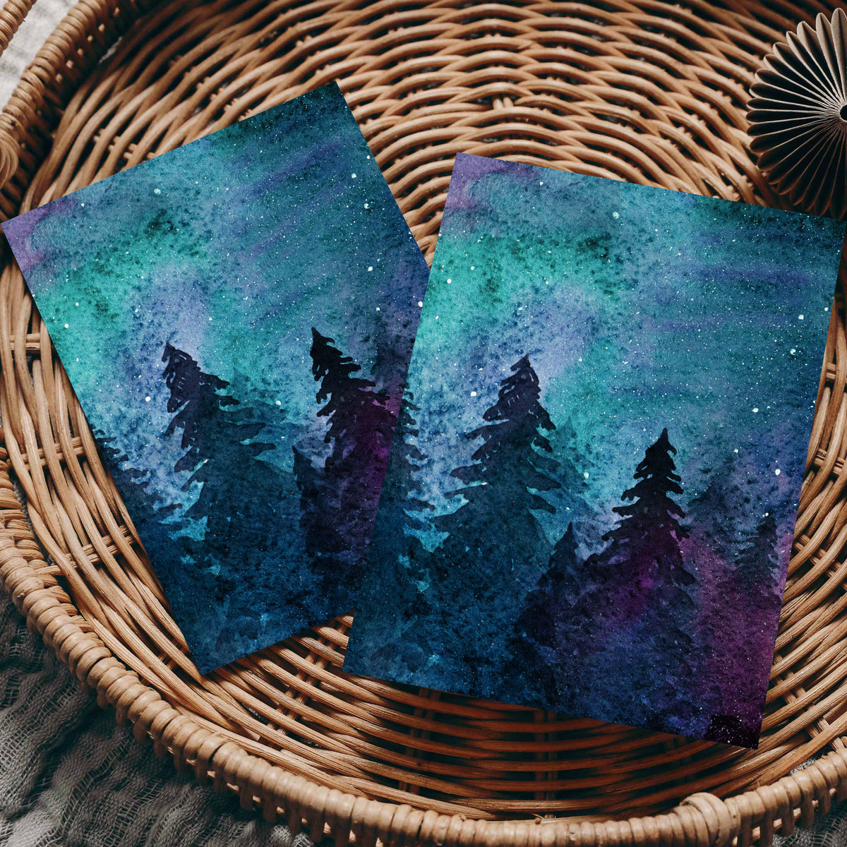 Set of 24 folded cards with a full-bleed night sky design in teal, purple, and magenta over silhouetted trees.