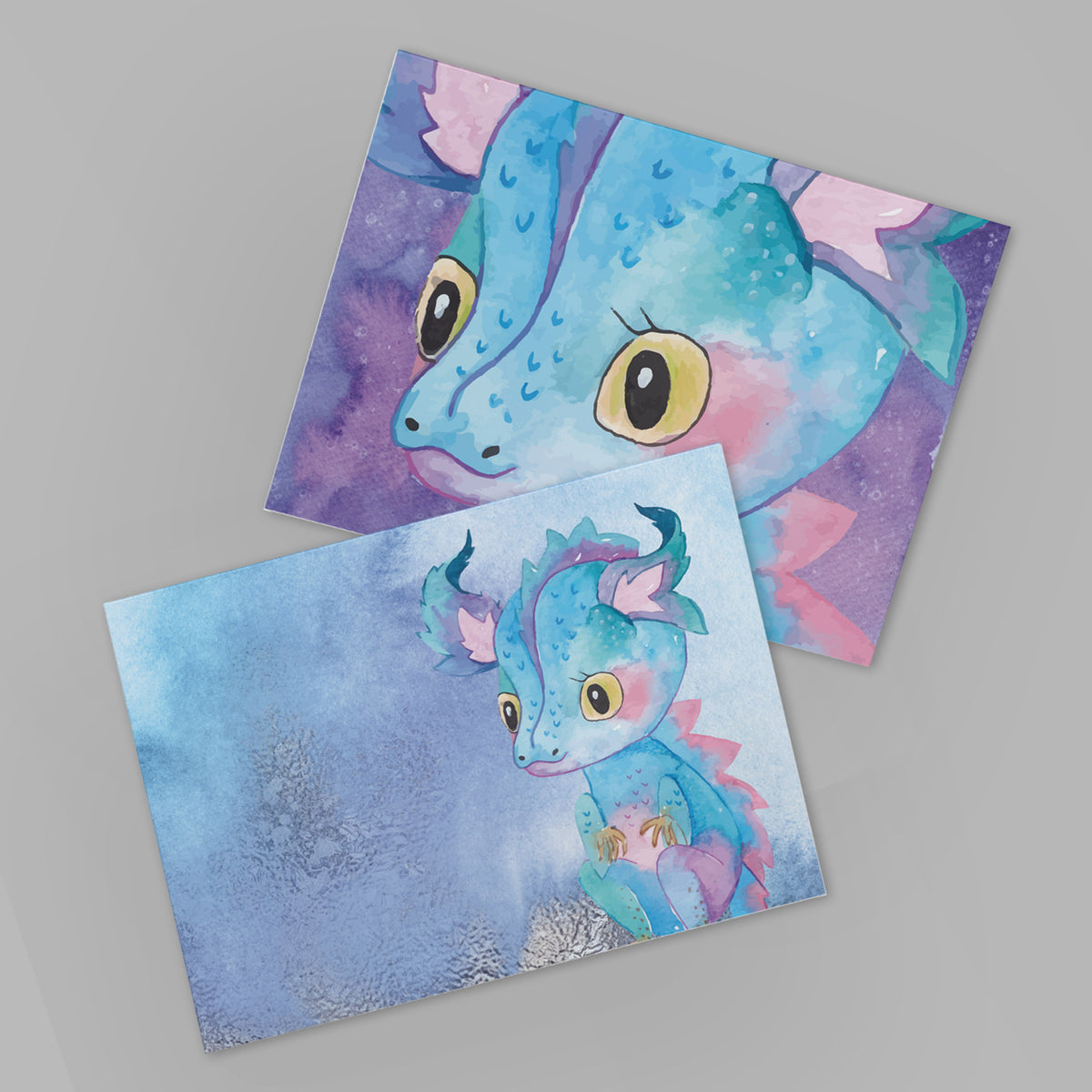 Folded notecards with full-bleed watercolor dragon illustrations in blue, teal, pink, purple, and gold tones.