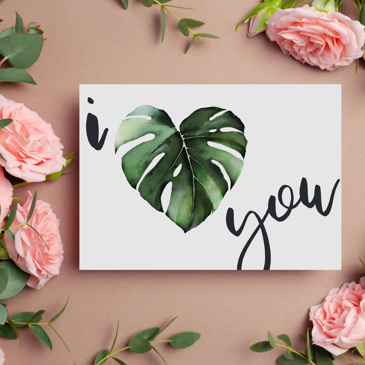 Monstera leaf shaped like a heart printed between the words "i" and "you" in black handwritten script.
