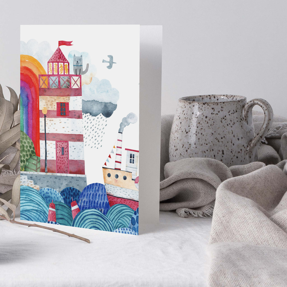 Watercolor harbor scene card showing a lighthouse, rainbow, gray cat on balcony, and stylized waves.