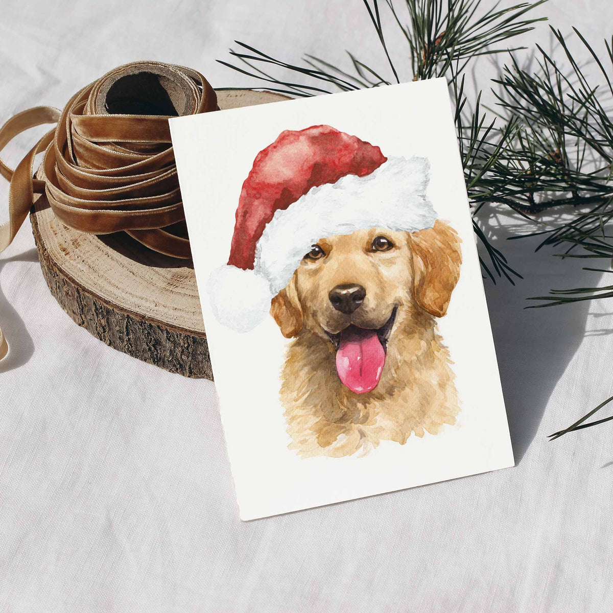 Golden retriever with an open mouth and pink tongue, painted in honey and amber washes, in a tilted red Santa hat.