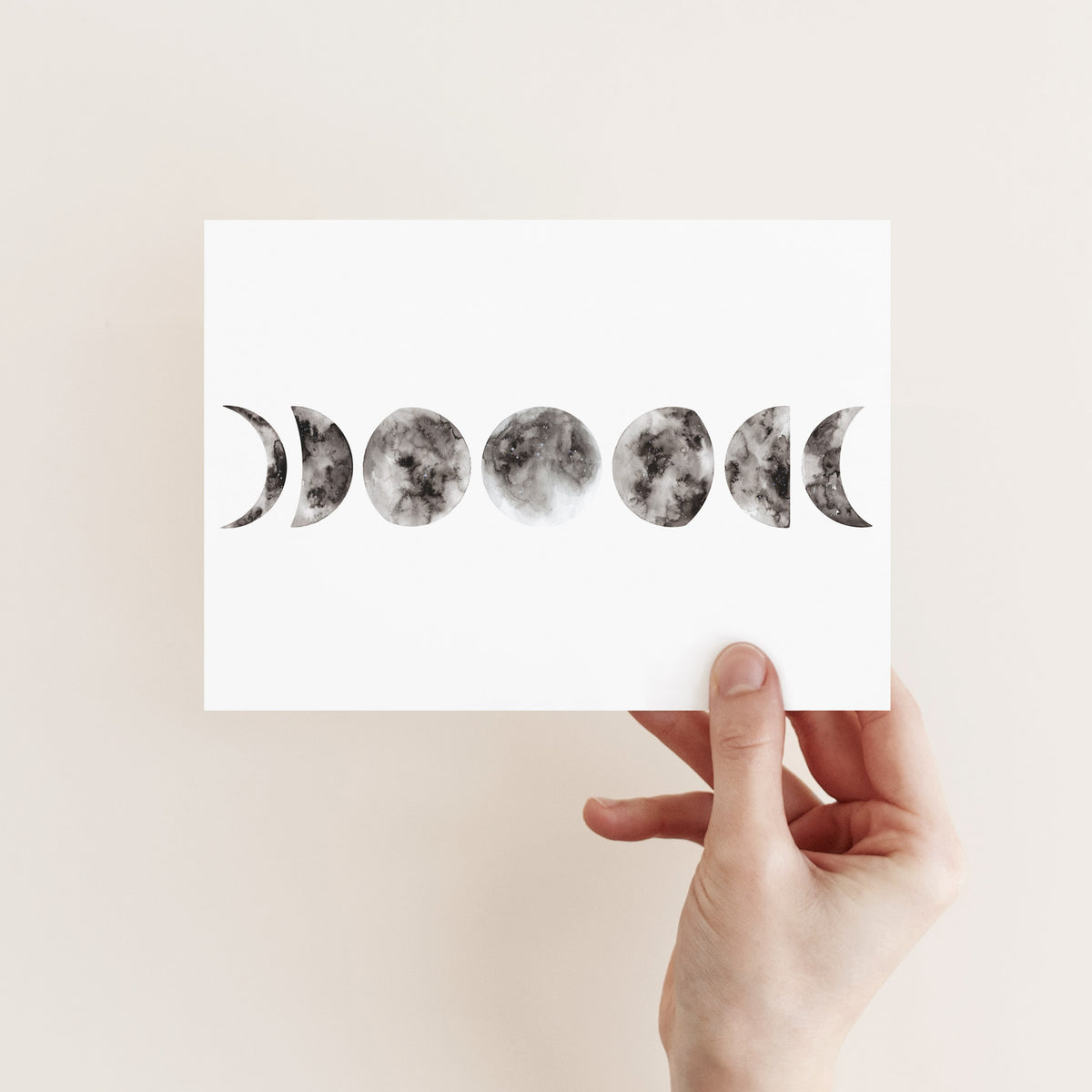 Folded greeting cards showing a horizontal moon phases design in black, gray, and white tones.