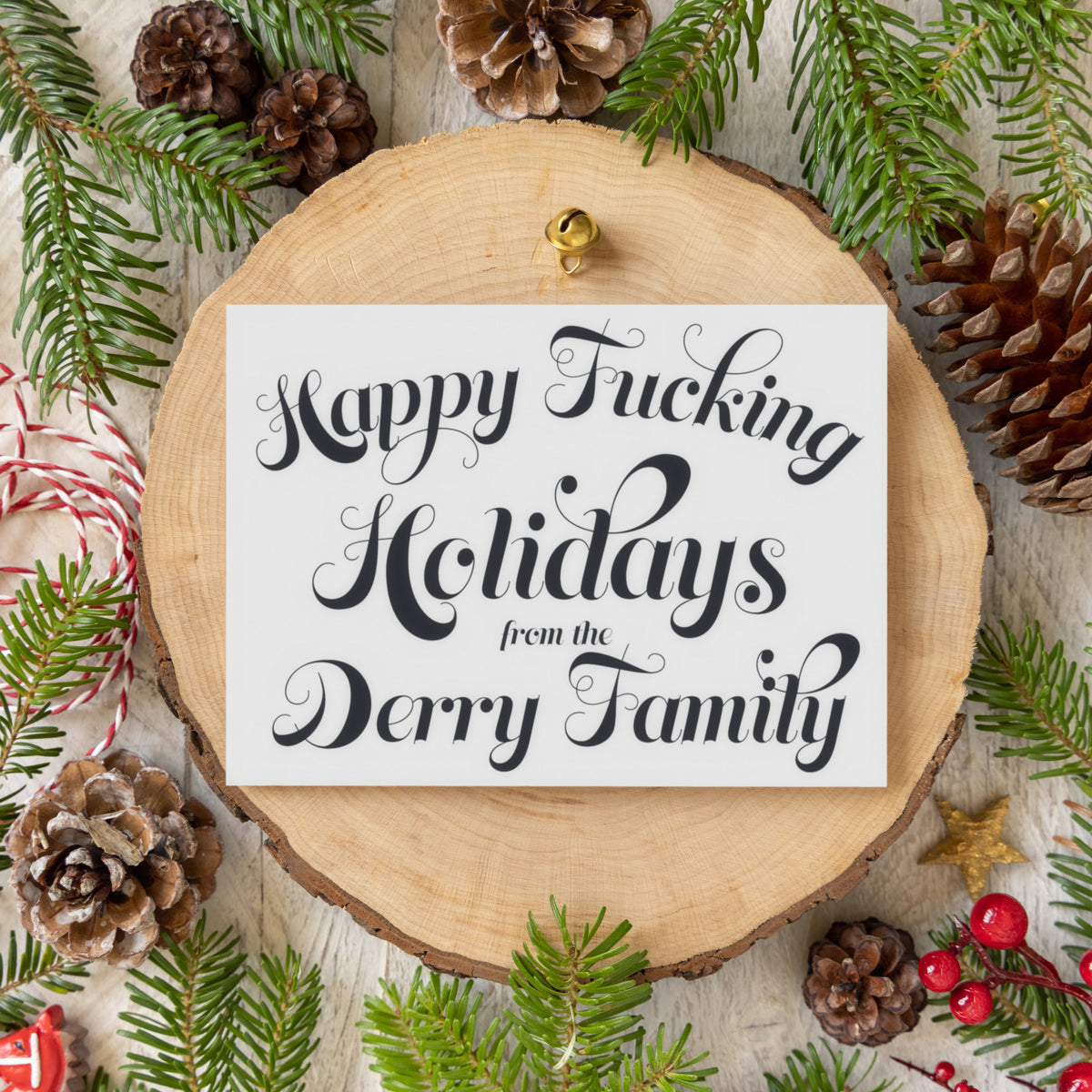 Text-only Christmas card with four centered lines of black ornate script on white, personalized with family surname.
