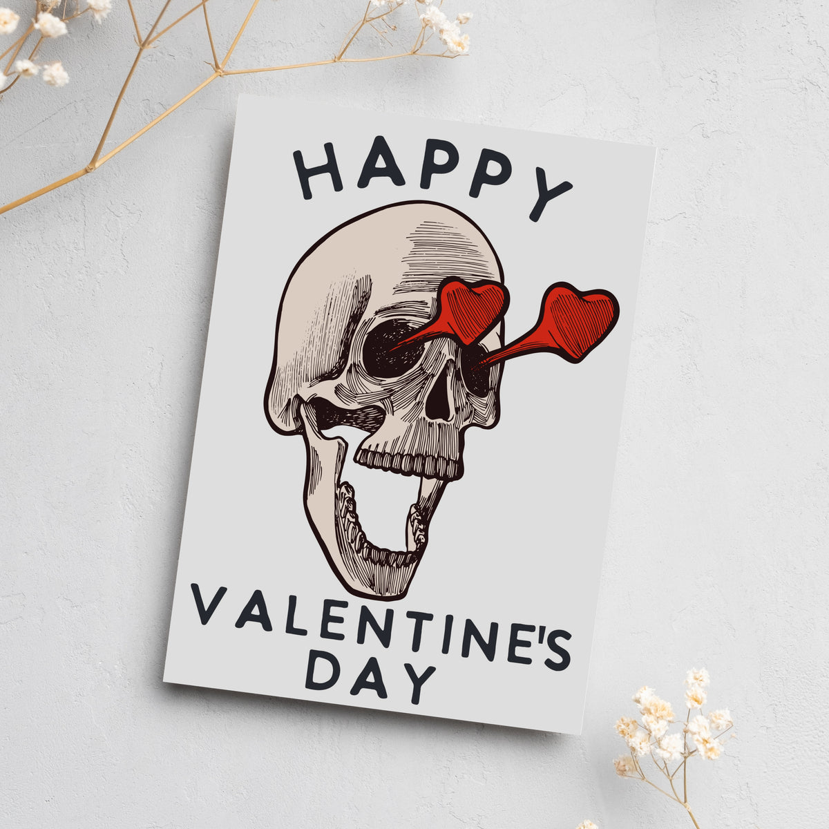 Boxed set of 24 matching cards showing a skull in linework style with heart glasses and stacked block-letter holiday text.