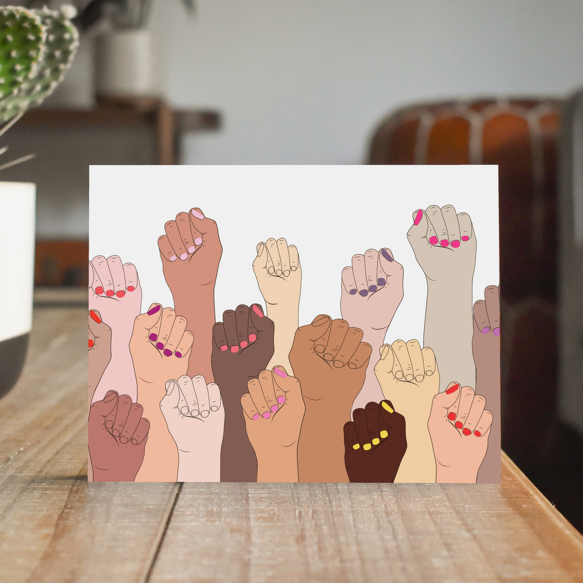 Identical cards printed with a full-bleed illustration of raised fists with colorful painted nails.