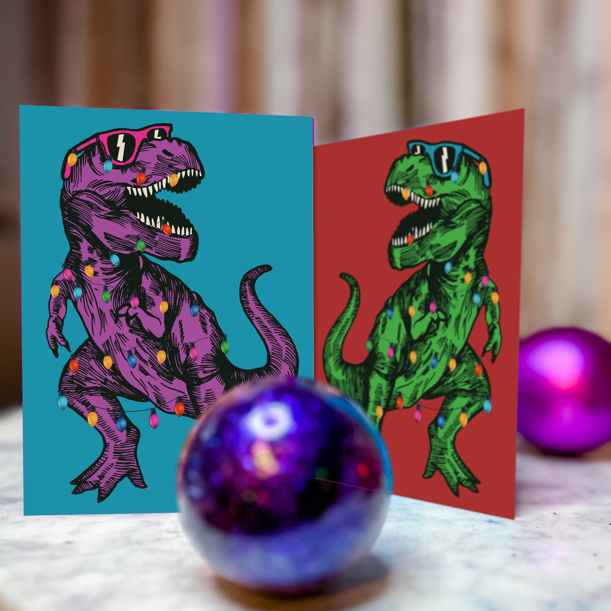 Two-design holiday card set, 24 total, showing a striding T-Rex with open jaws and Christmas lights looped around it.