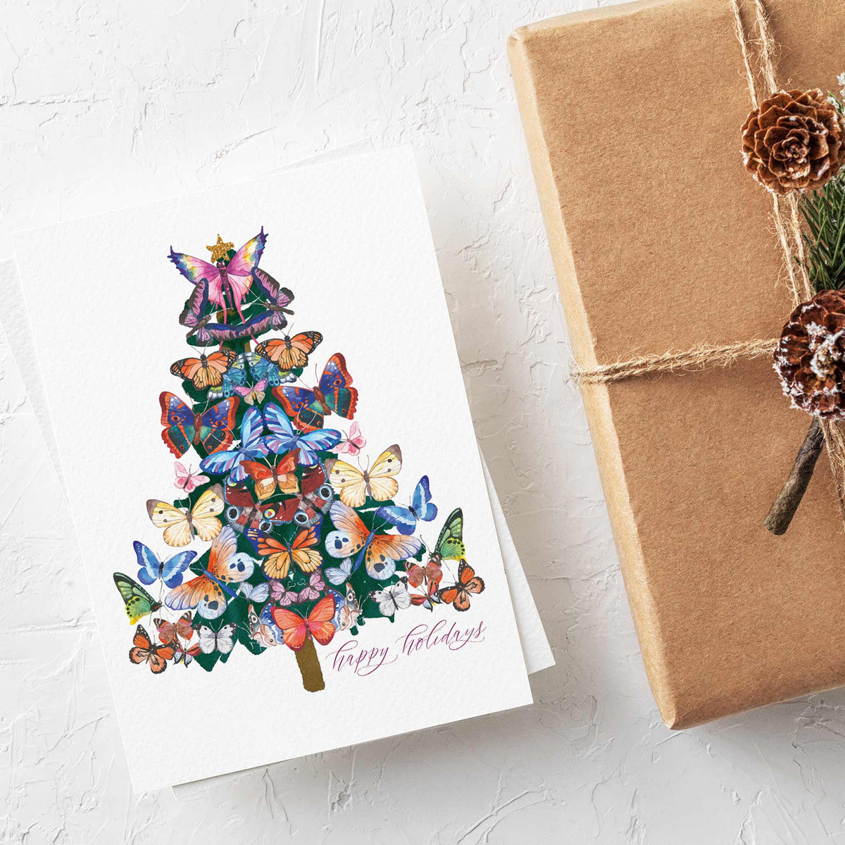 Single-design Christmas card set of 24 featuring a multicolor butterfly tree and pink cursive "Happy Holidays" greeting.