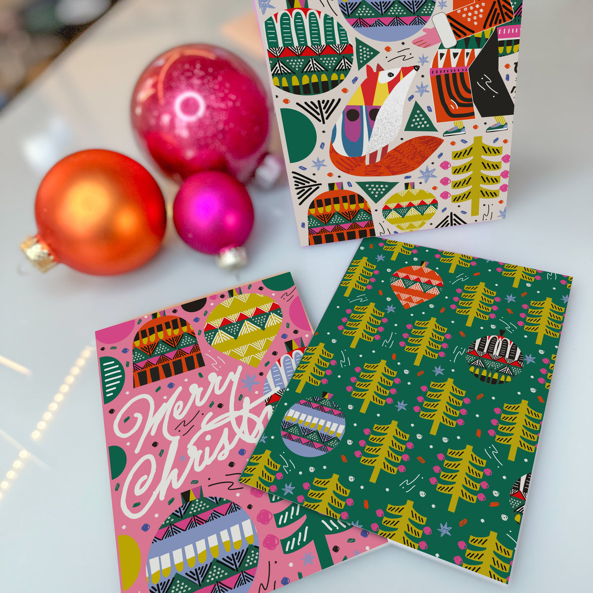 Christmas cards with patterned round ornaments, striped hanging ornaments, and dotted evergreen trees.