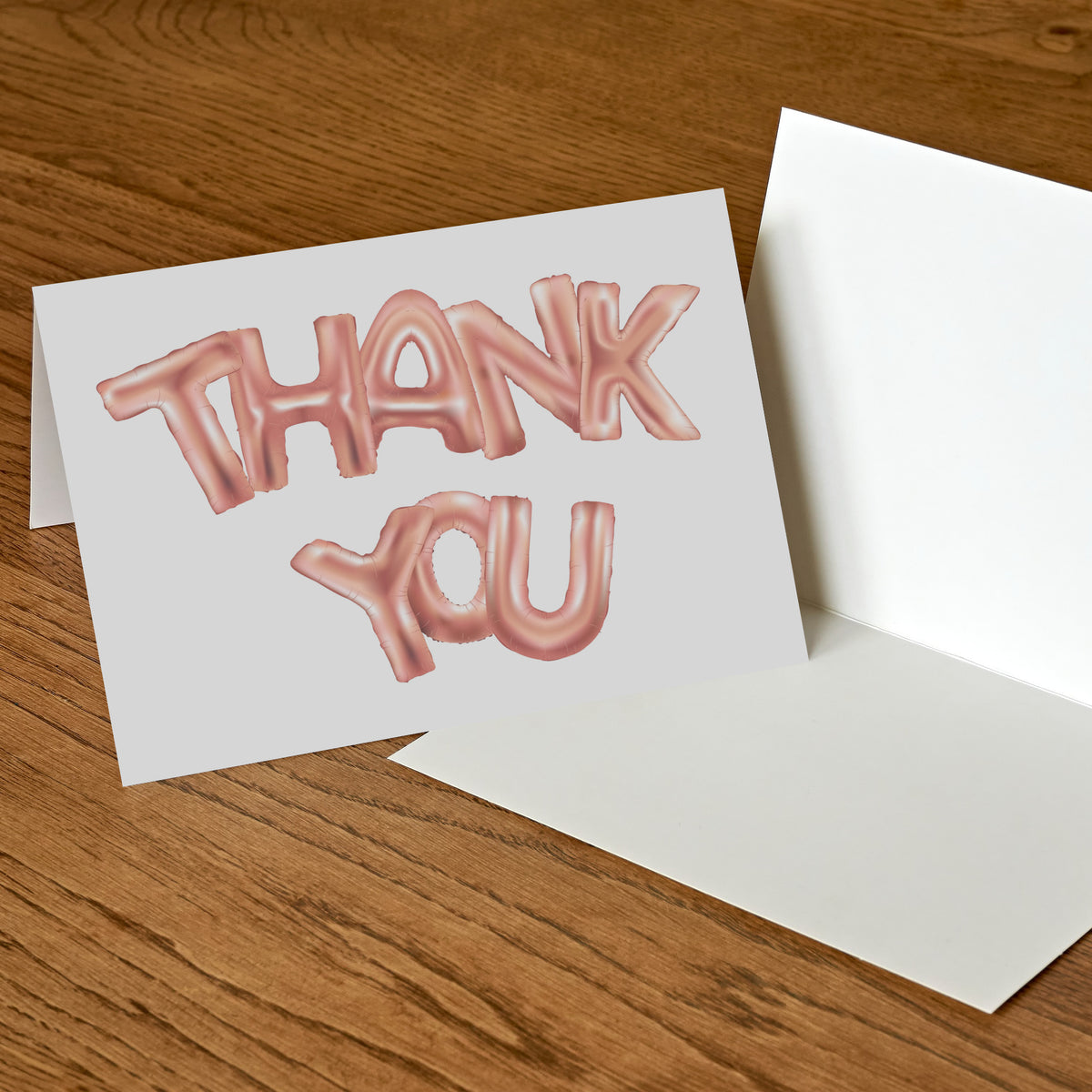 White folded greeting cards with THANK YOU in bold sans-serif balloon lettering, rose gold metallic.