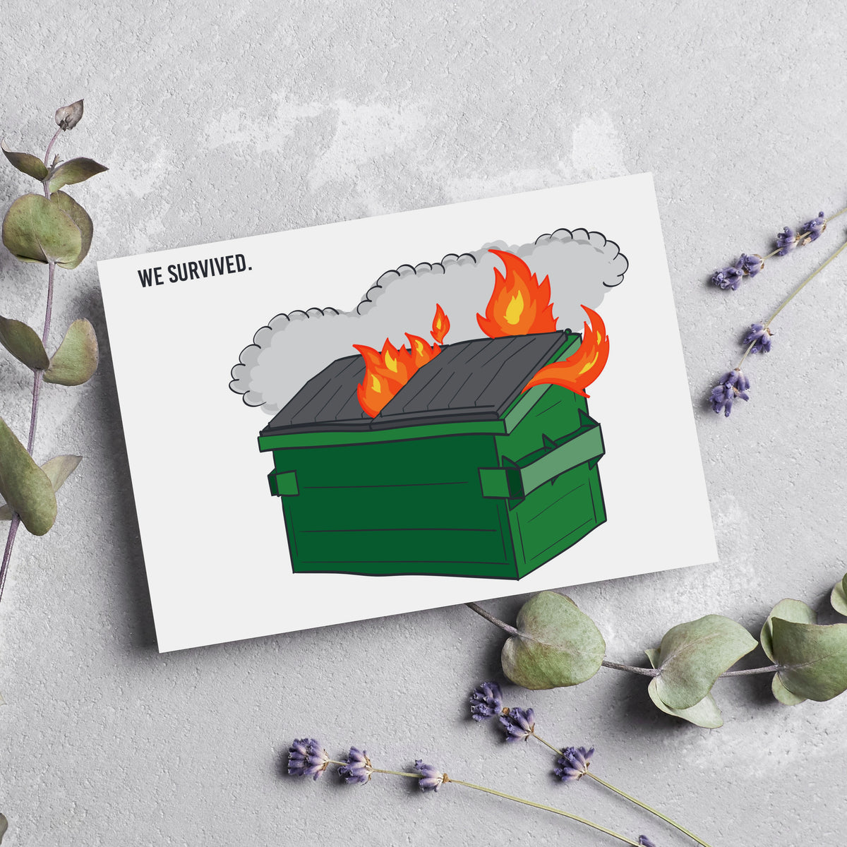 Single-design card set reading WE SURVIVED. alongside a green dumpster illustration with orange, red, and yellow flames erupt