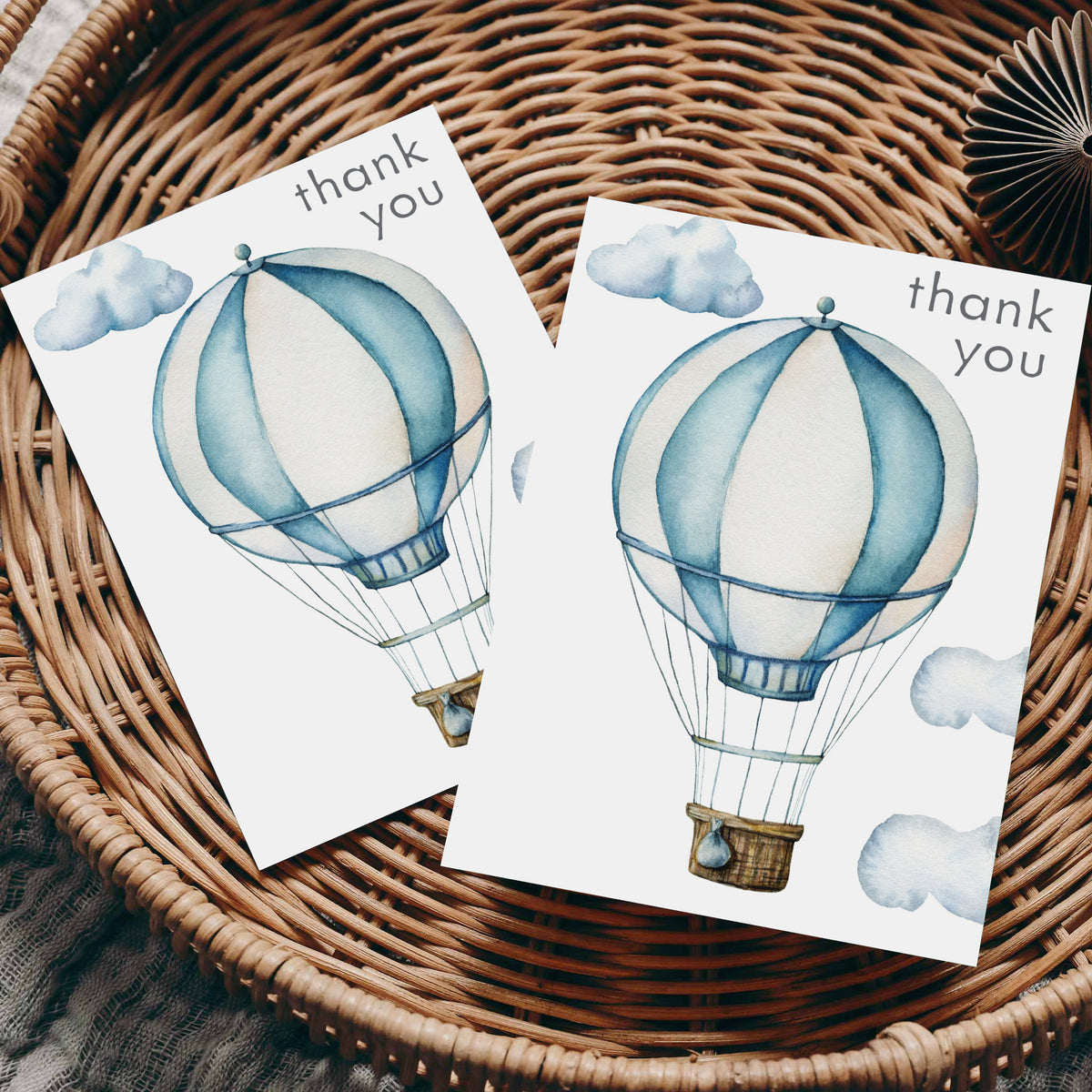 Thank you card, white background, hot air balloon illustration left-center, two-line "thank you" in lowercase sans-serif text