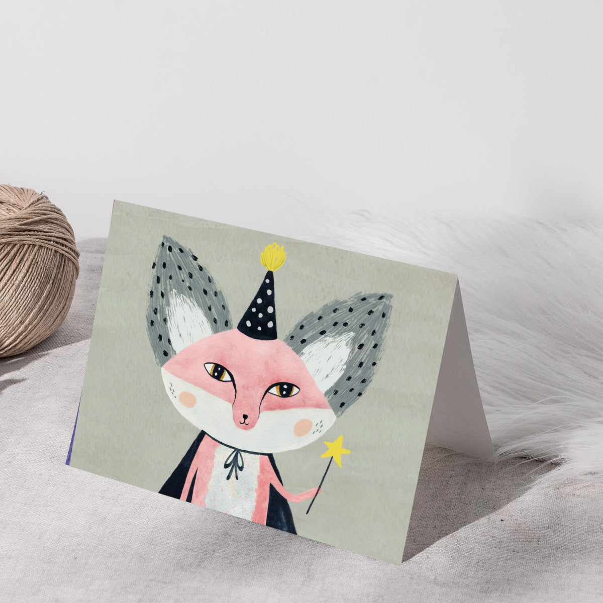 Watercolor-style fox character card with gray stippled ears, navy hat, white bow at collar, and yellow star wand.