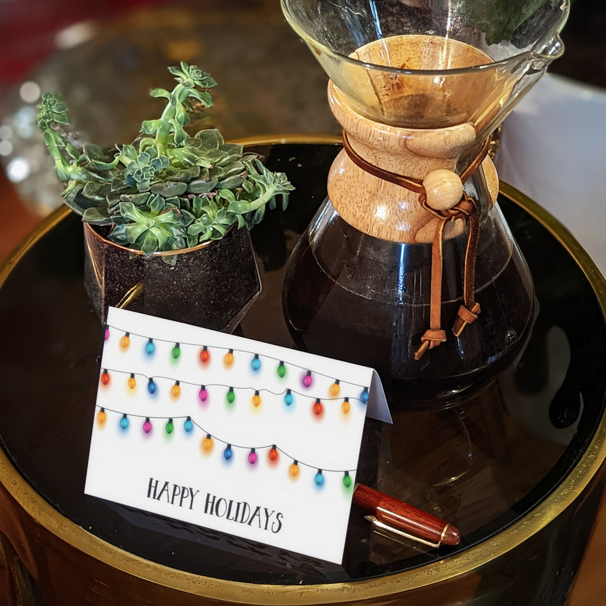 Holiday card with multicolor oval bulbs on black sockets arranged across three horizontal hanging strands.