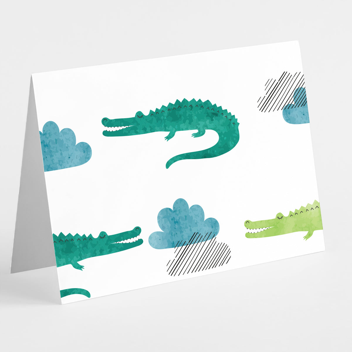 Card boxed set, two crocodilian repeat designs with open-mouthed figures and watercolor cloud shapes.