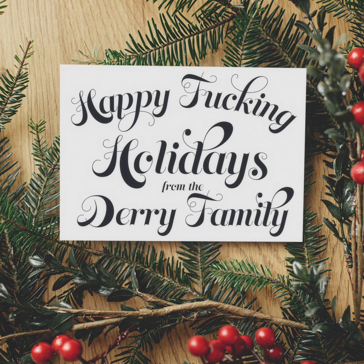 Black ornate script holiday card with hairline swash flourishes, personalized surname, landscape top-fold format.