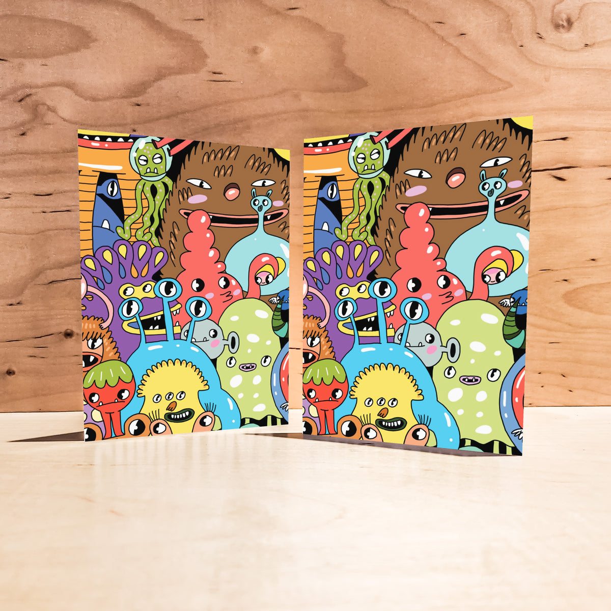 Identical greeting cards with a dense, colorful crowd of outlined cartoon creatures and monsters.