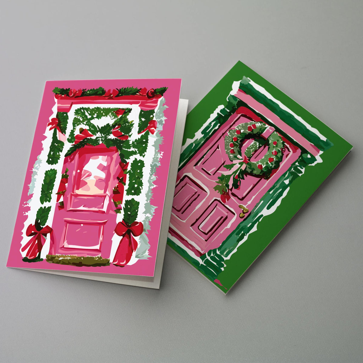 Pack of 24 illustrated Christmas cards showing pink front doors with holiday wreaths and garland on solid-color backgrounds.