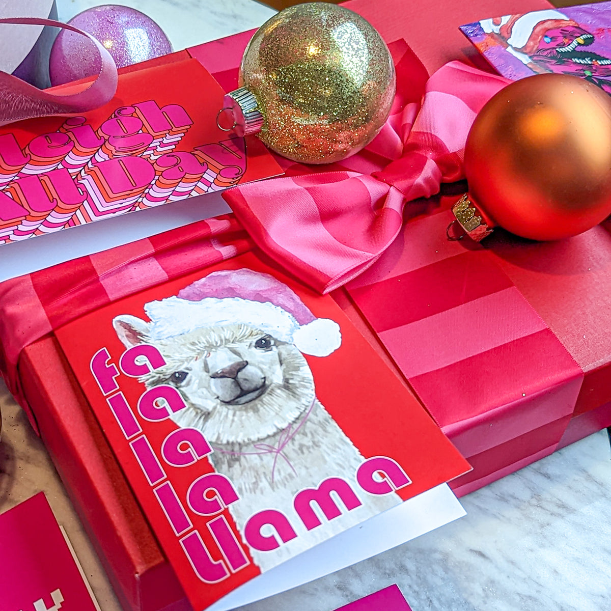 Holiday greeting cards with magenta, red, and purple backgrounds paired with white, pink, and orange lettering.
