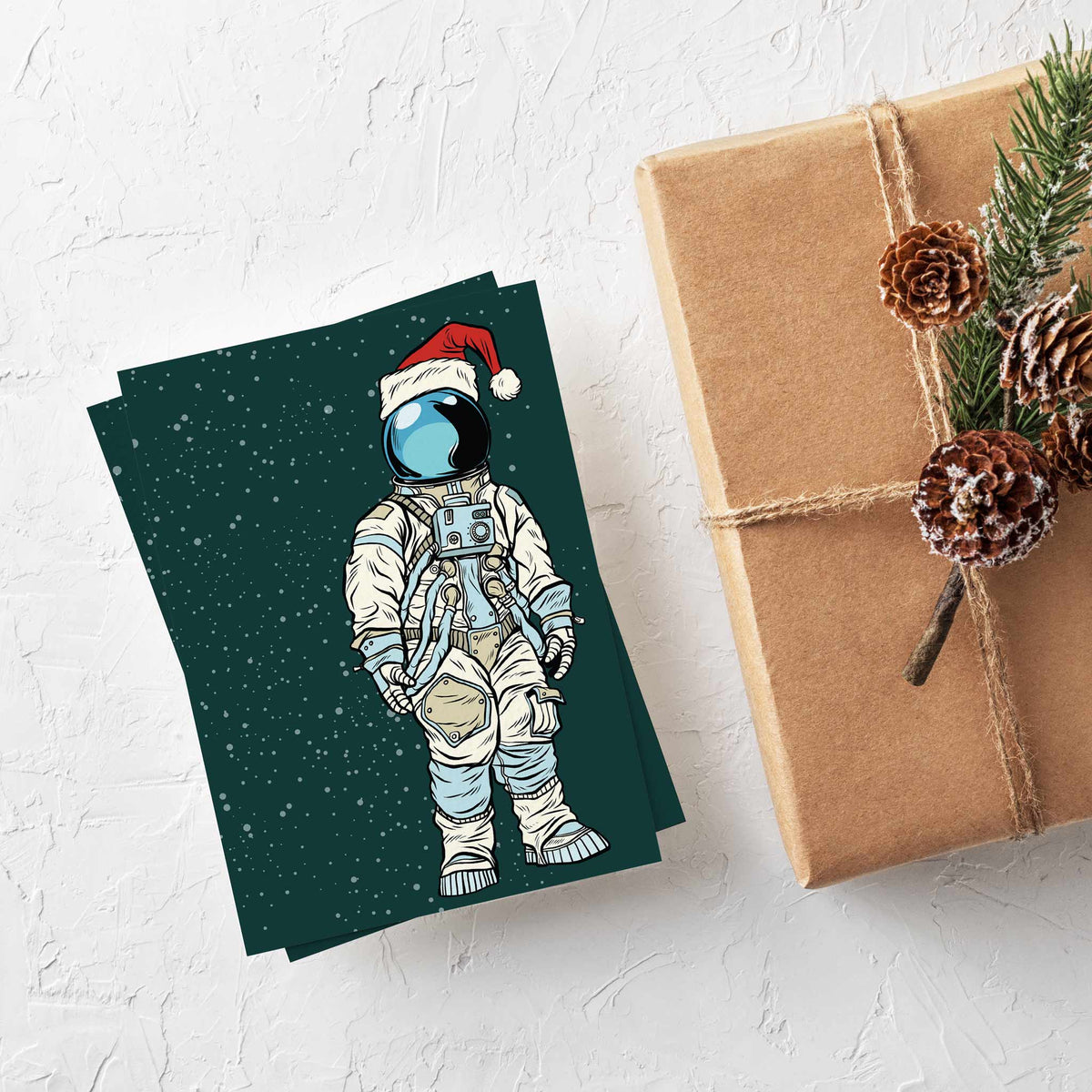 Illustrated astronaut in full space suit with chest panel and hoses, wearing Santa hat, on starry teal card.