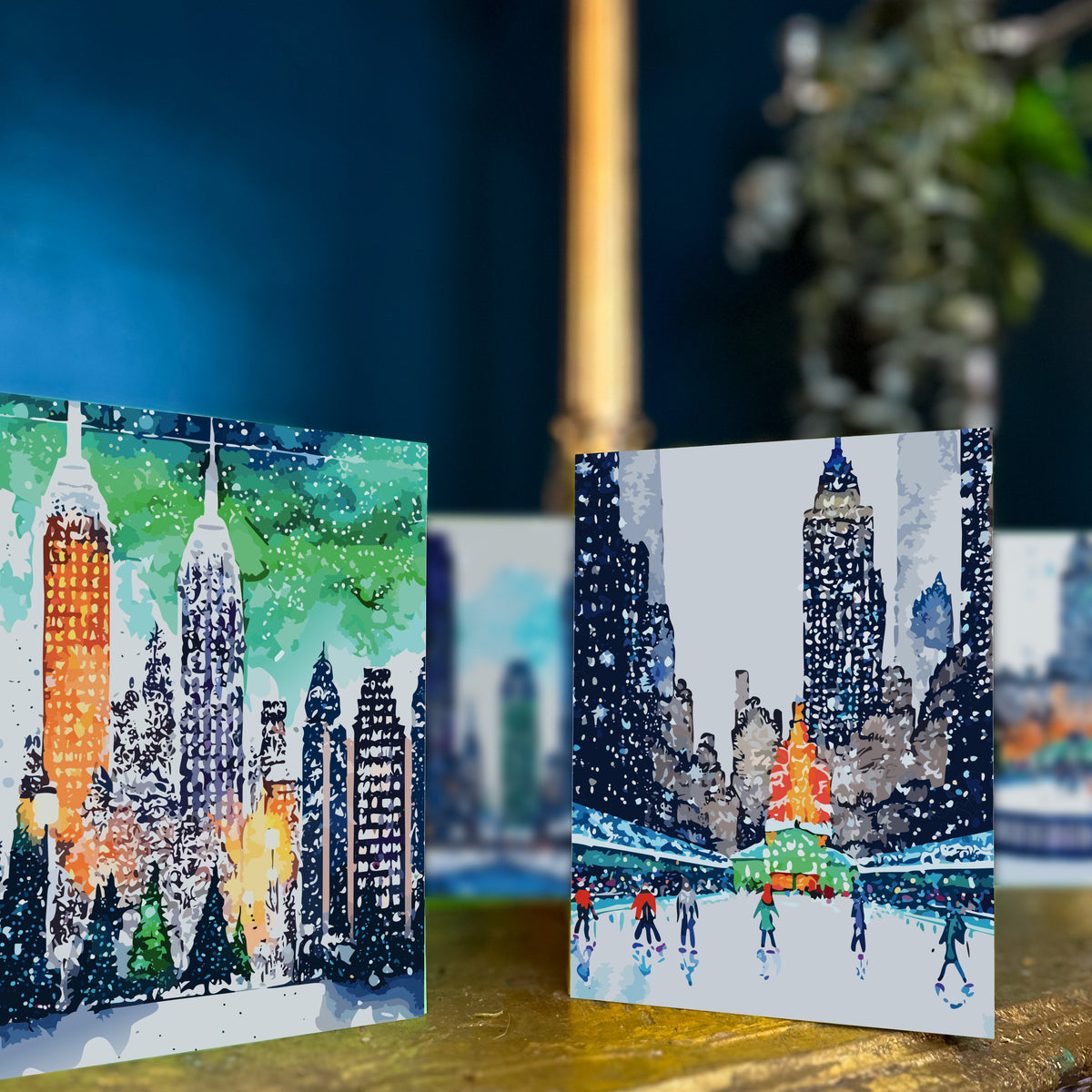 Card set with six New York City winter designs in navy, teal, green, and gray watercolor illustration style.