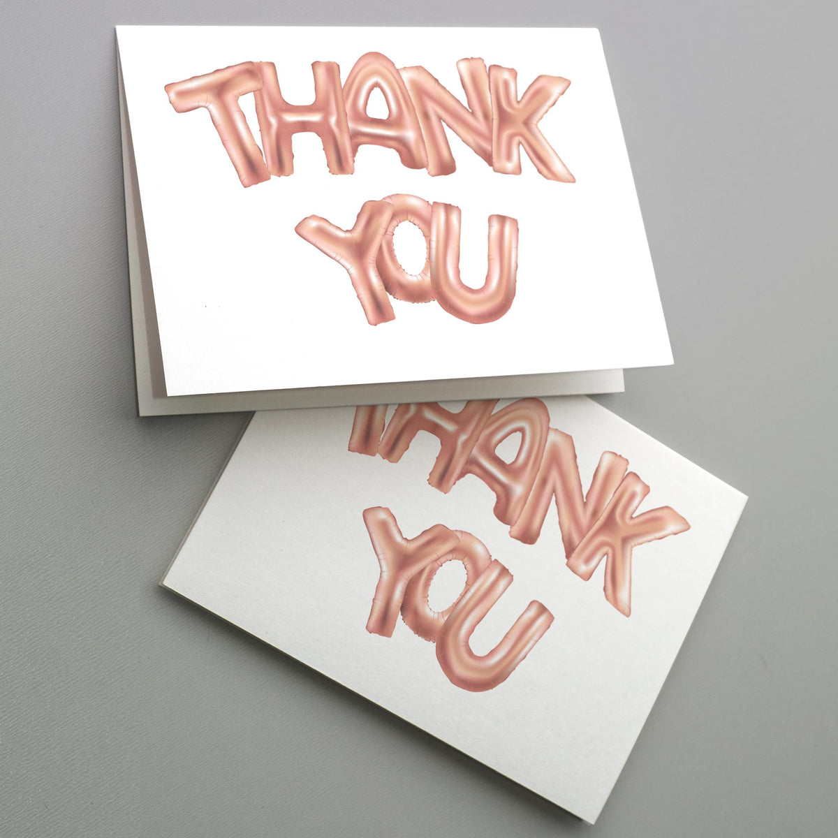 Folded white note cards with rose gold balloon lettering spelling THANK YOU, set of 24.