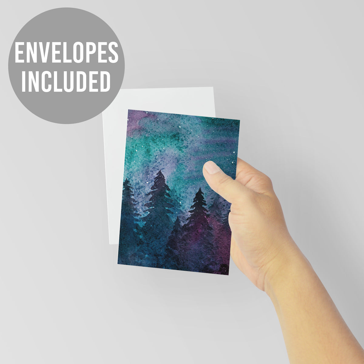 Holiday card with no text, full-bleed watercolor scene, evergreen silhouettes, and a multicolor night sky.
