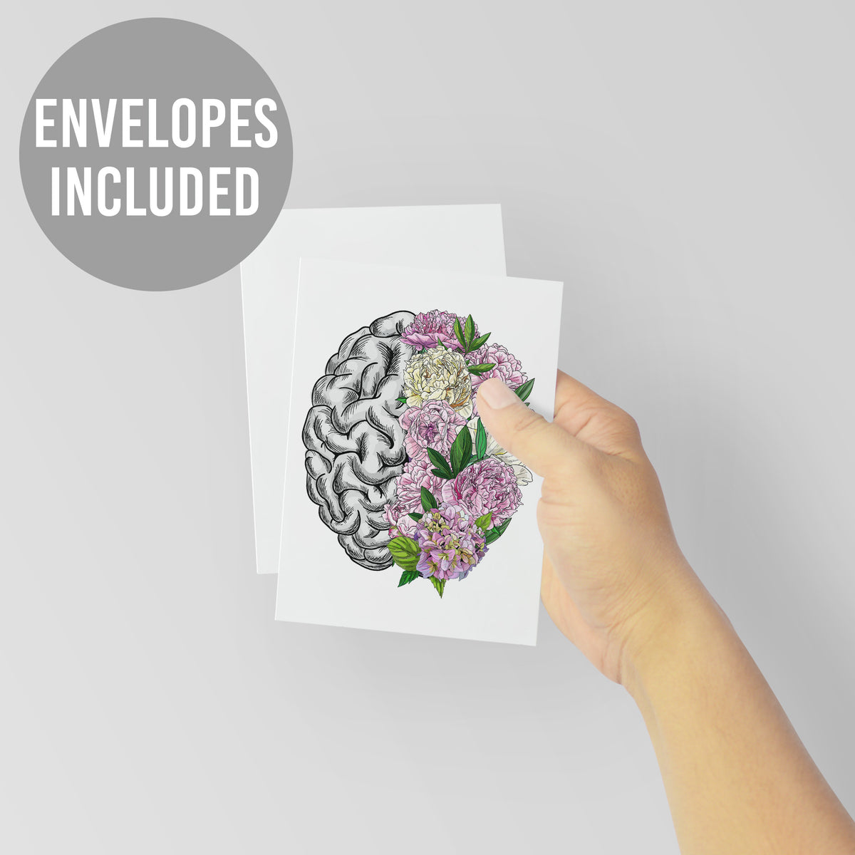 White greeting card with a centered brain split between black-and-white anatomical detail and blooming peonies in pink and iv