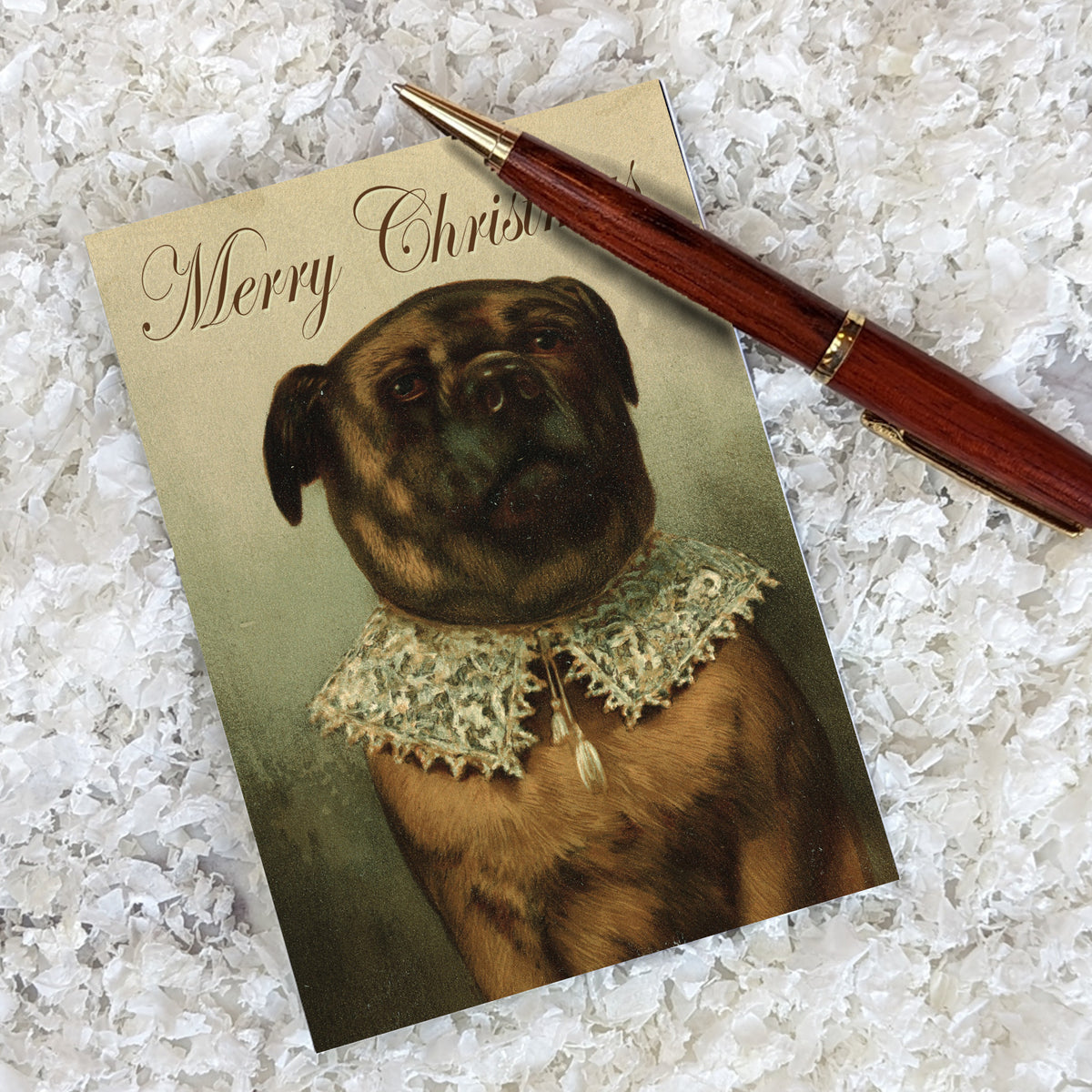 Christmas card showing a brindle pug's chest-up portrait, tilted head, brown eyes, and "Merry Christmas" in script above.
