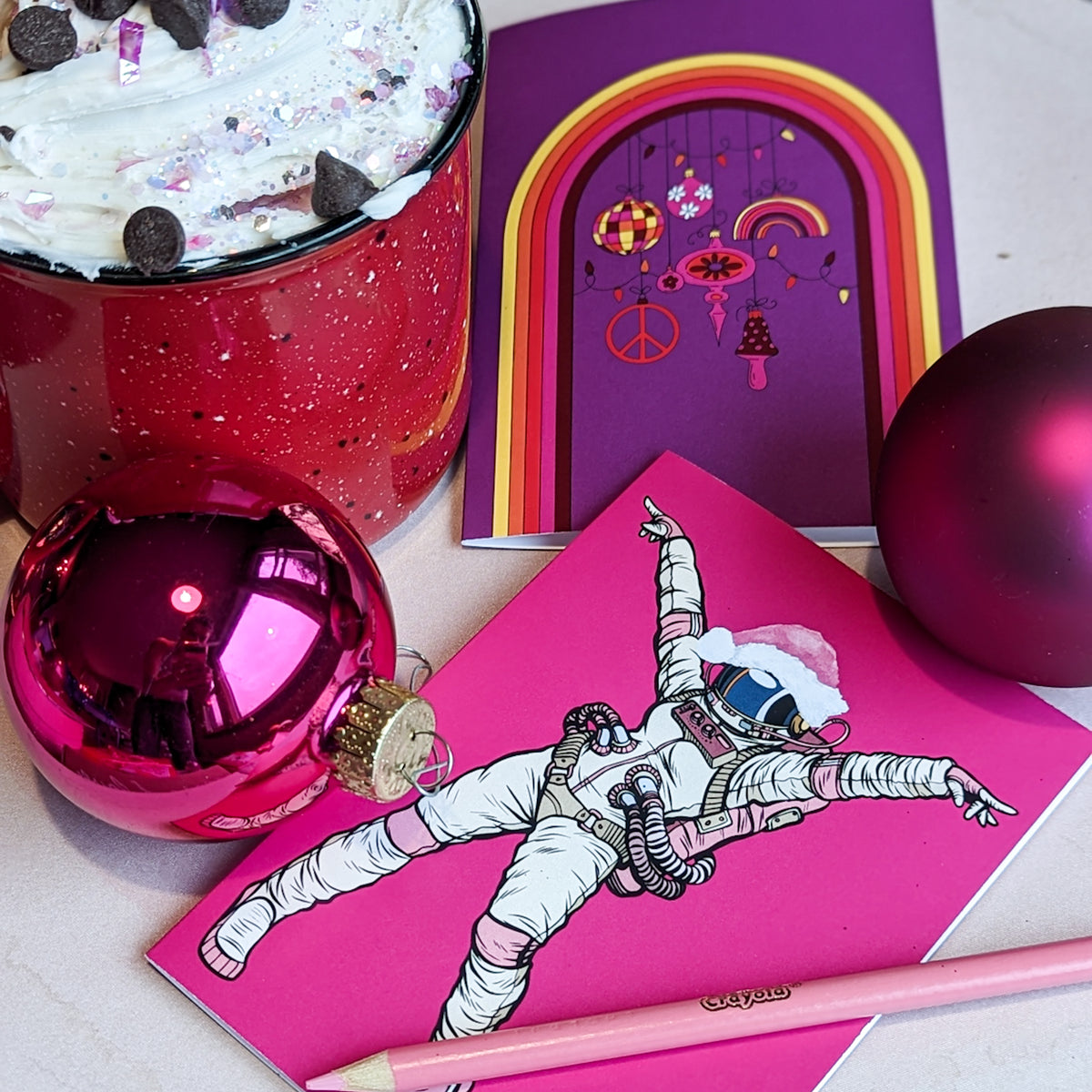 Christmas cards featuring retro and eclectic designs including rainbow arches, shooting stars, and Santa hats.